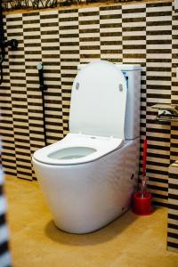 a white toilet in a bathroom with a red brush at Villa Andaz in Negombo