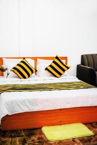 a bed with black and white pillows and a yellow rug at Villa Andaz in Negombo