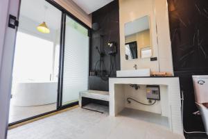 a bathroom with a sink and a tub and a mirror at Kirin Sky Resort in Khao Kho