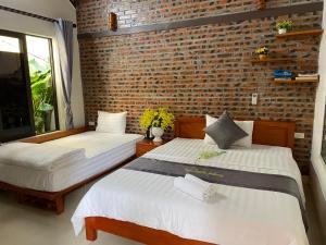 two beds in a room with a brick wall at Center Tam Coc Homestay in Ninh Binh