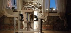 a book shelf with books and a cat sitting on it at L'angolo di Filippo I in Cividale del Friuli