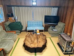 a living room with a tree stump coffee table at 愛犬と家族みんなでのんびり羽休めv古民家民泊OMOTENASHI LODGe 悠遊 in Nakafurano