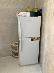 a white refrigerator in a corner of a room at Reef Alhamra in Al Ḩamrāʼ