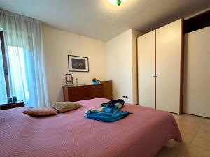 a bedroom with a pink bed with a bag on it at Residenza Porta Del Mare in Lignano Sabbiadoro