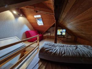 a attic room with a bed and a tv at Bel appartement rénové (Le Nichoir) in Cornimont