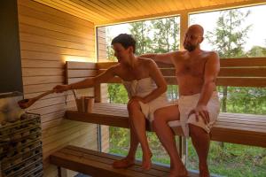 two men sitting on a bench in a sauna at Cozy houses - Sauga Fishing Village riverside holiday center in Pärnu
