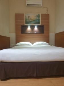 Schlafzimmer mit einem großen Bett mit einem Kopfteil aus Holz in der Unterkunft Violand Garden Hotel Samarinda in Samarinda