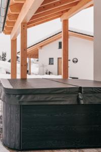 einen schwarzen Tisch auf einer Terrasse mit einem Dach in der Unterkunft Chalets Woid_Liebe&Glück in Bodenmais