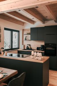 eine Küche mit schwarzen Geräten und einer Holzdecke in der Unterkunft Chalets Woid_Liebe&Glück in Bodenmais