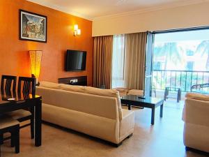 a living room with a couch and a tv at Susegad Suites Goa Apartments & Villas Riviera Hermitage Arpora in Arpora