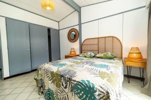 ein Schlafzimmer mit einem Bett und einem Tisch mit einer Lampe in der Unterkunft Villa 400m2, 10 pers St Clotilde in Saint-Denis