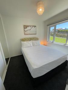 um quarto com uma grande cama branca e uma janela em Central Howick Uxbridge Apartments em Auckland