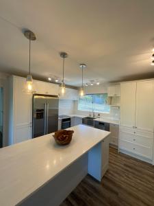 una cocina con armarios blancos y un bol en una encimera en Central Howick Uxbridge Apartments, en Auckland