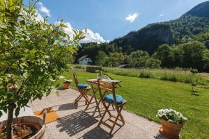 un patio con mesa, sillas y césped en Pr'Kovač 2 /Perfect stay for 2, en Bohinjska Bela