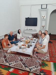 un gruppo di persone seduti intorno a un tavolo di Doppi a Khiva