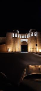 un edificio de noche con un coche delante en Doppi, en Khiva