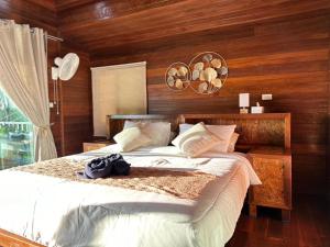 閣遙島的住宿－บ้านสวนปิยนันท์ (Baansuan Piyanan)，一间卧室配有一张带木墙的大床