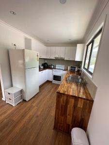 a kitchen with white cabinets and a white refrigerator at Peak View in Lithgow