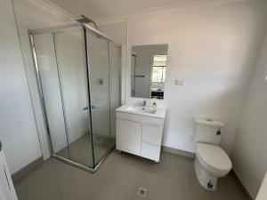 a bathroom with a shower and a toilet and a sink at Peak View in Lithgow