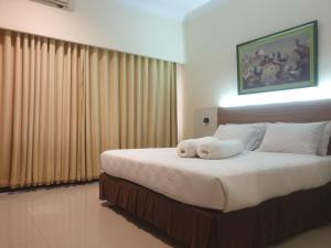una camera da letto con un grande letto con lenzuola bianche di Violand Garden Hotel Samarinda a Samarinda