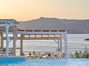 a swimming pool with a pavilion and the ocean at Mykonos Lolita, A Grecotel Resort to Live in Agios Sostis Mykonos
