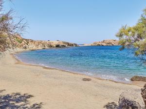 a beach with blue water and trees on it at Mykonos Lolita, A Grecotel Resort to Live in Agios Sostis Mykonos
