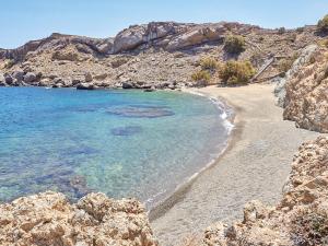 a sandy beach with blue water and rocks at Mykonos Lolita, A Grecotel Resort to Live in Agios Sostis Mykonos