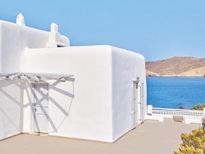a white building with a view of the water at Mykonos Lolita, A Grecotel Resort to Live in Agios Sostis Mykonos