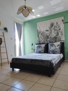a bedroom with a bed with a painting on the wall at TERLA Bel Appartement 3 Pieces Clim & Parking in Saint-Pierre