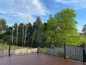 a black fence on a deck with trees at Auckland GQ Flat bush holiday home in Auckland
