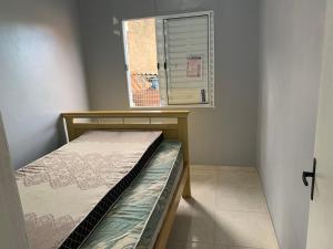a small bedroom with a bed and a window at Casa de Praia in Tramandaí