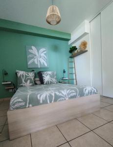 um quarto com uma cama com uma parede verde em TERLA Bel Appartement 3 Pieces Clim & Parking em Saint-Pierre