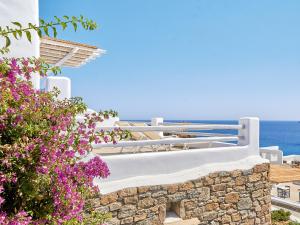 a balcony with flowers and the ocean in the background at Mykonos Lolita, A Grecotel Resort to Live in Agios Sostis Mykonos