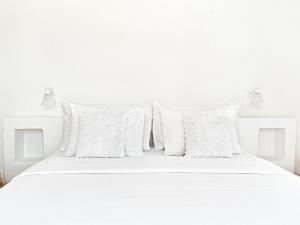 a white bed with white pillows on it at Mykonos Lolita, A Grecotel Resort to Live in Agios Sostis Mykonos