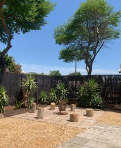 a patio with a bench and trees in front of a fence at Apartment with garden, and garage in Cape Town