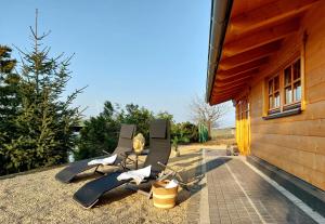 - un ensemble de chaises sur une terrasse à côté d'un bâtiment dans l'établissement Ferienhaus Schilz, à Plütscheid