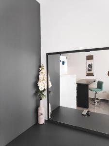 een spiegel in een kamer met een bureau en een vaas met bloemen bij RELAX&DREAM apartment Long Beach in Saint Yeorgios