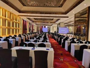 a banquet hall with white tables and black chairs at Blue Bell Hotel - Greater Noida in Greater Noida