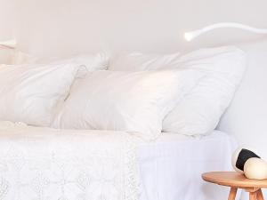 a white bed with white pillows on it at Mykonos Lolita, A Grecotel Resort to Live in Agios Sostis Mykonos