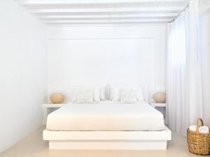 a white bedroom with a white bed and a window at Mykonos Lolita, A Grecotel Resort to Live in Agios Sostis Mykonos