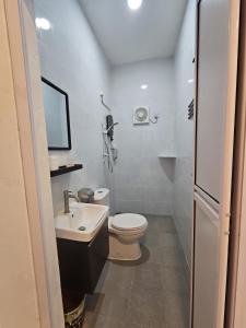 a white bathroom with a toilet and a sink at Guest House Gua Kelam in Kaki Bukit