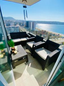 Un balcón con sofás y mesas y vistas al océano. en Departamento frente a la playa full amoblado, en Coquimbo