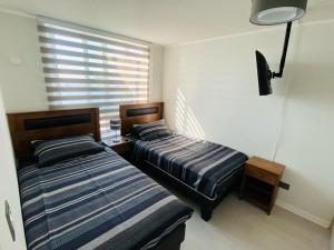 2 camas en una habitación con ventana en Departamento frente a la playa full amoblado, en Coquimbo