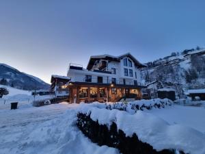 a house in the snow at dusk at SKILL Mountain Lodge - Ski und Bike Hostel inklusive JOKER CARD in Saalbach-Hinterglemm
