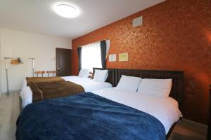 two beds in a room with orange walls at HDO Hachiken Villa in Sapporo