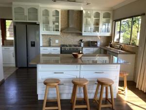 a kitchen with white cabinets and wooden stools at The Bell's in the Berg in Underberg