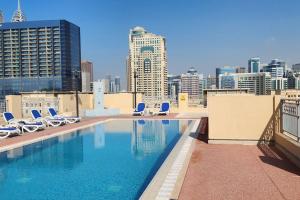 a swimming pool on the roof of a building with chairs at Lake View The Greens & Views in Dubai