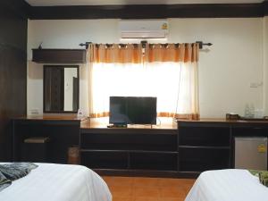 1 dormitorio con 1 cama y ventana con TV en เฮือนคำรีสอร์ท บูติค โฮเทล แม่สาย เชียงราย en Chiang Rai