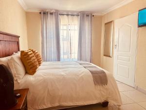 ein Schlafzimmer mit einem weißen Bett mit einem Fenster in der Unterkunft MBT Guesthouses in Ga-Mothiba + 10 Fotos