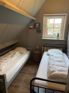 two beds in a small room with a window at Vakantiehuis Hof Molenzicht in Oostkapelle